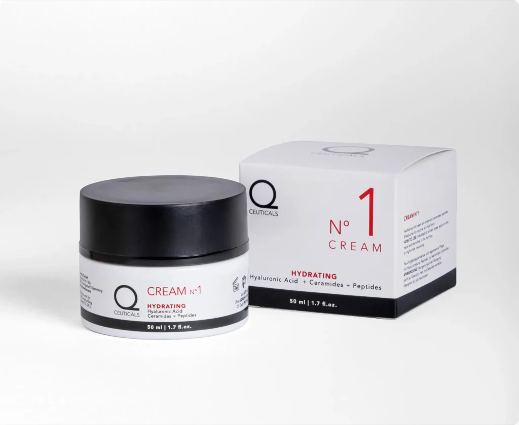 A jar of Q Ceuticals No. 1 Hydrating Cream is elegantly presented next to its sleek white and red packaging, embodying the luxurious essence of cosmetic creams. The black jar, adorned with a white label, contains 50 ml (1.7 fl oz) of cream enriched with hyaluronic acid, ceramides, and peptides.